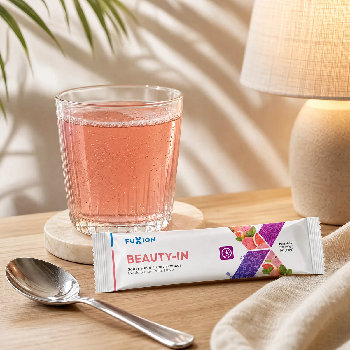 Vaso de Beauty-In rosado y un stick sobre una mesa de luz con lámpara encendida